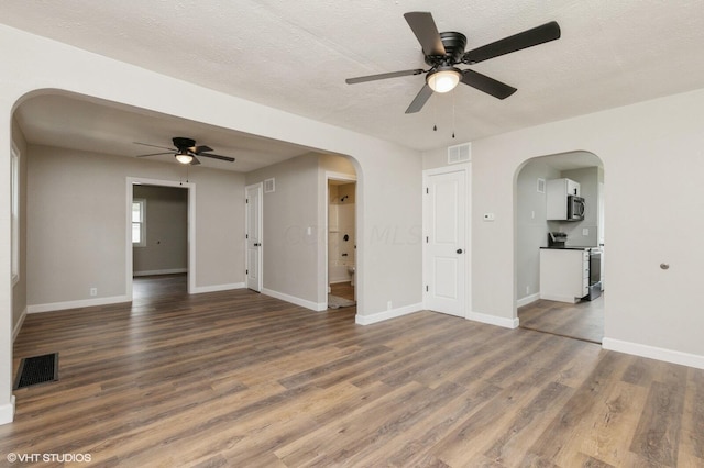 unfurnished living room featuring dark hardwood / wood-style floors, ceiling fan, and a textured ceiling