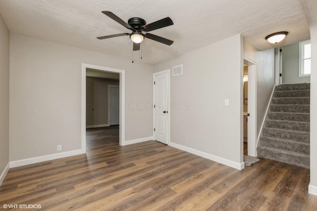 empty room featuring a textured ceiling, dark hardwood / wood-style flooring, and ceiling fan