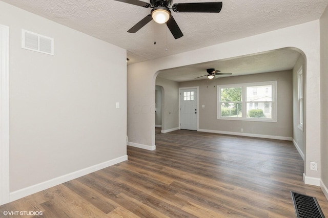 unfurnished room featuring a textured ceiling, ceiling fan, and dark wood-type flooring