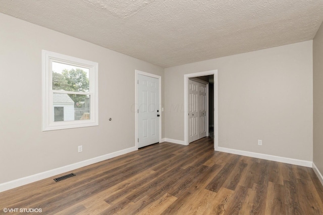 empty room with dark hardwood / wood-style flooring and a textured ceiling