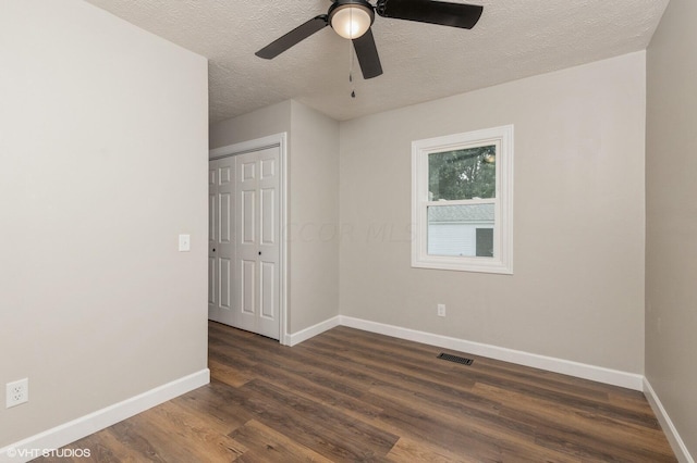 empty room featuring a textured ceiling, ceiling fan, and dark wood-type flooring