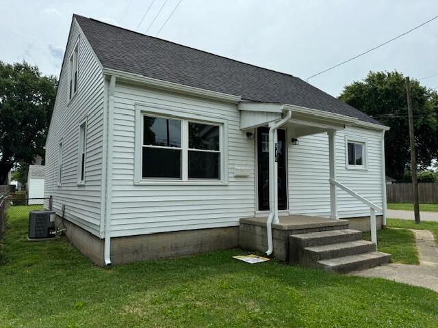 view of front of house with a front lawn and cooling unit