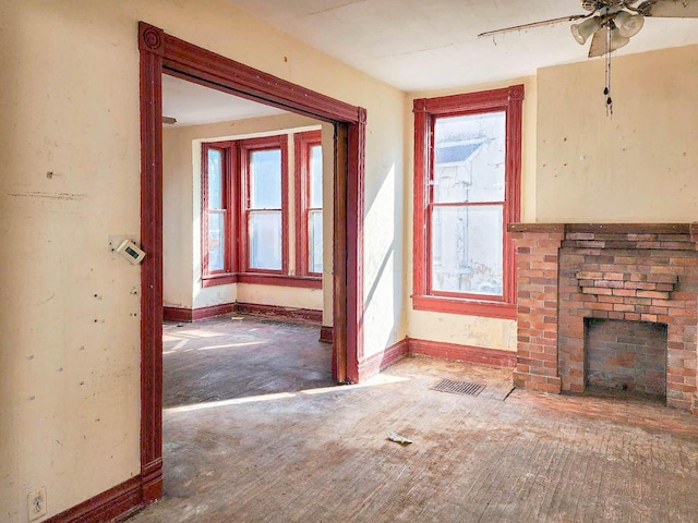 unfurnished living room with ceiling fan, a healthy amount of sunlight, and a brick fireplace