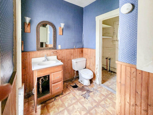 bathroom with parquet flooring, vanity, toilet, and wood walls