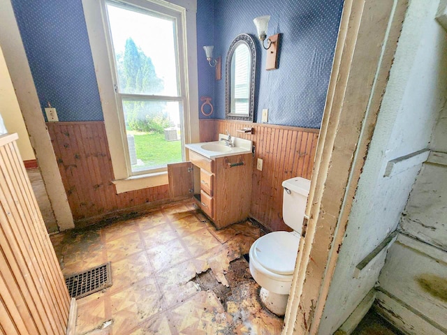 bathroom with vanity, wood walls, and toilet