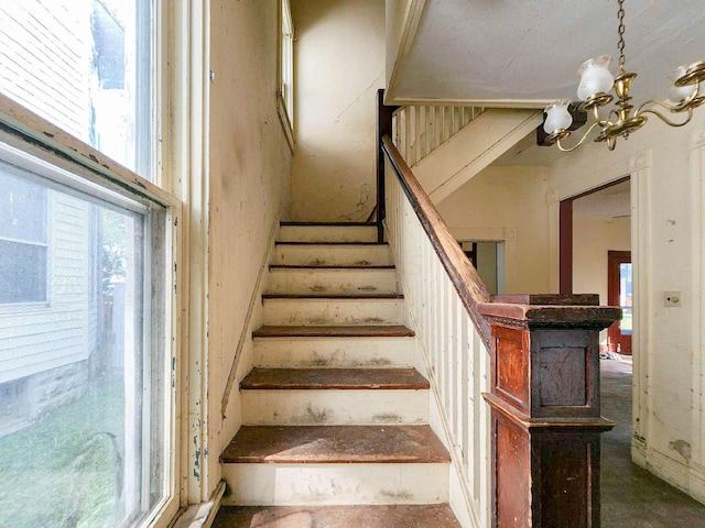 staircase with a notable chandelier