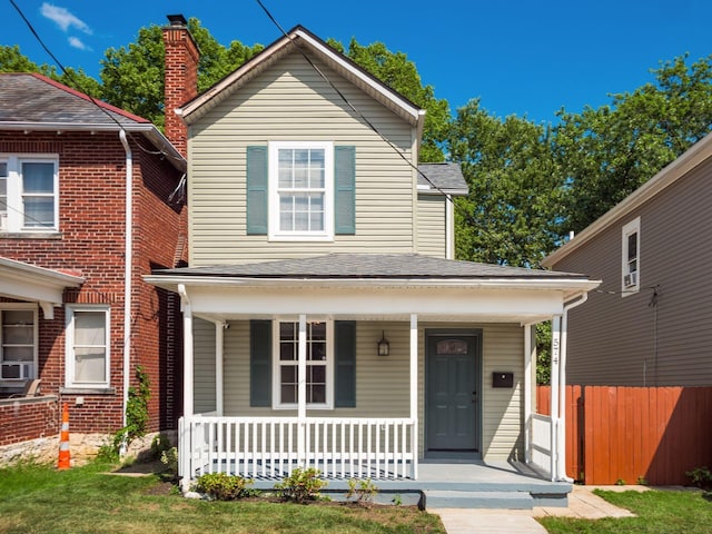 view of front of property featuring a shingled roof, fence, and a porch