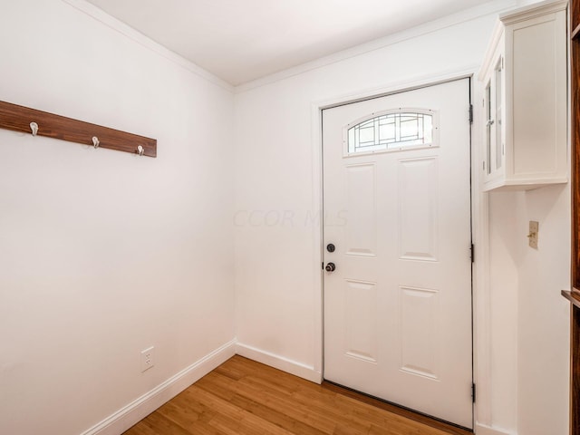 doorway with light hardwood / wood-style flooring and crown molding