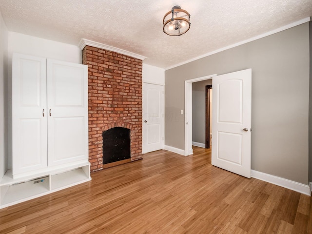 unfurnished living room with a brick fireplace, a textured ceiling, light hardwood / wood-style flooring, and crown molding