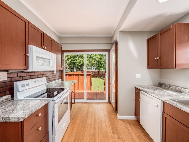 kitchen with light wood-type flooring, white appliances, and sink