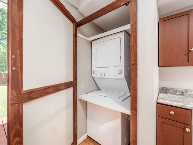 clothes washing area with stacked washer / dryer and light hardwood / wood-style flooring