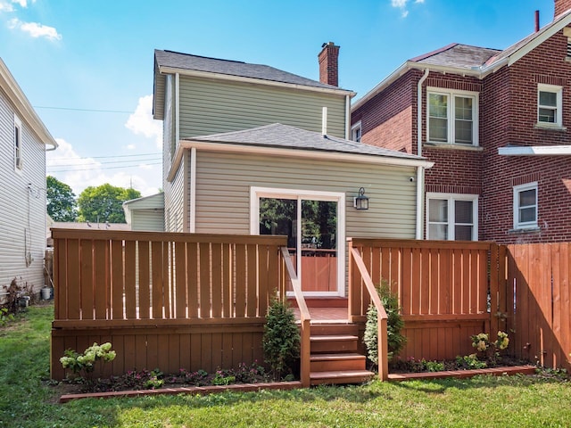 rear view of property featuring a lawn and a deck