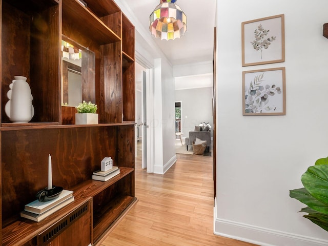 hallway with ornamental molding, baseboards, and light wood-type flooring