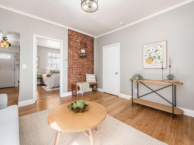 sitting room with baseboards, crown molding, and light wood-style flooring