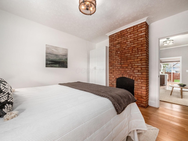 bedroom featuring crown molding, light wood-style floors, and a textured ceiling