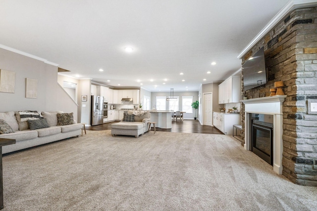 carpeted living room featuring a large fireplace and ornamental molding