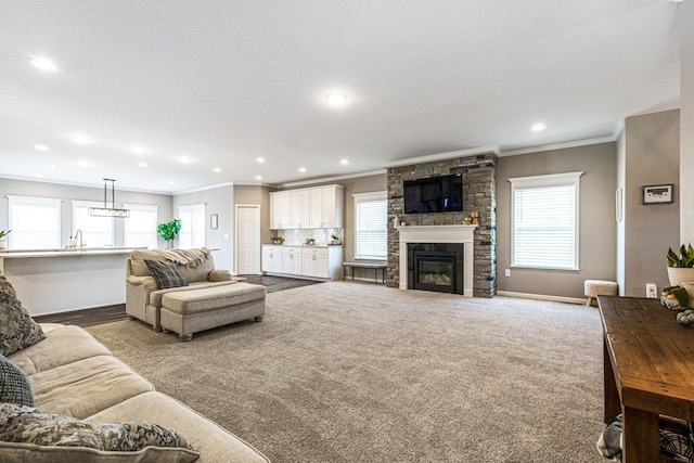 carpeted living room with a fireplace, sink, crown molding, and a wealth of natural light