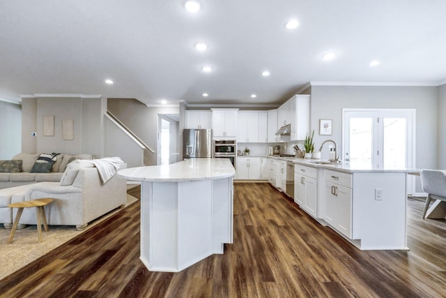 kitchen with sink, a kitchen island, dark hardwood / wood-style flooring, white cabinets, and appliances with stainless steel finishes