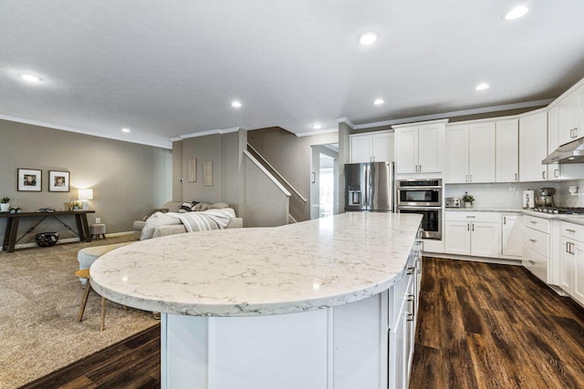 kitchen with appliances with stainless steel finishes, dark hardwood / wood-style flooring, crown molding, white cabinetry, and a kitchen island