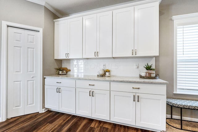 kitchen featuring white cabinets, crown molding, dark hardwood / wood-style floors, tasteful backsplash, and light stone counters