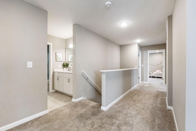 corridor with light colored carpet and a textured ceiling