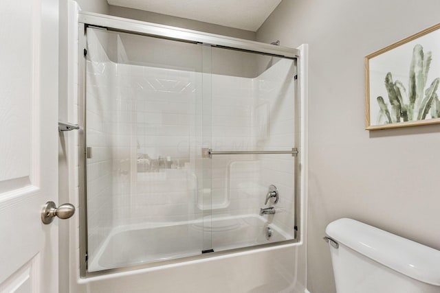 bathroom with bath / shower combo with glass door, a textured ceiling, and toilet