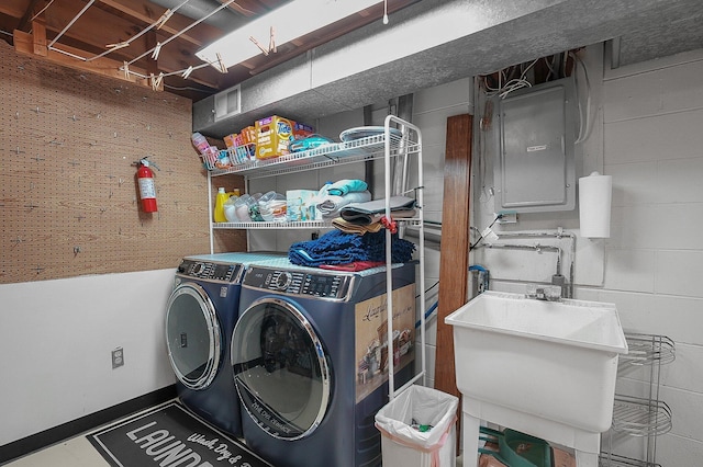 laundry area with electric panel, washer and clothes dryer, and sink