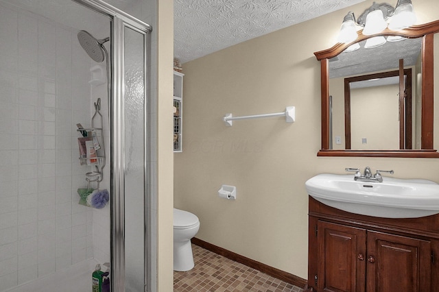 bathroom featuring vanity, toilet, a shower with shower door, and a textured ceiling