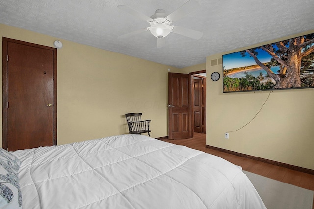 bedroom with ceiling fan, wood-type flooring, and a textured ceiling