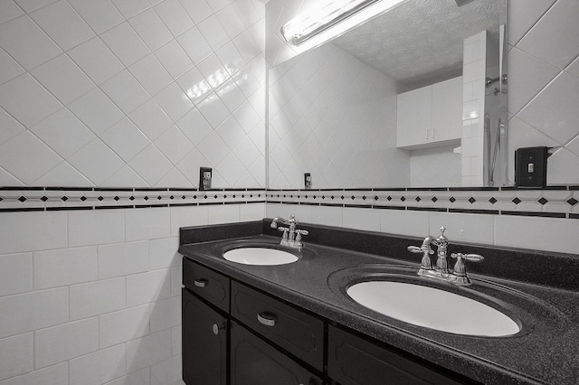 bathroom featuring vanity, tile walls, a textured ceiling, and decorative backsplash