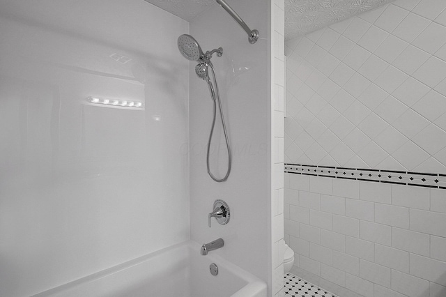 bathroom featuring tiled shower / bath combo, a textured ceiling, and toilet