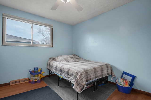 bedroom with hardwood / wood-style floors, a textured ceiling, and ceiling fan