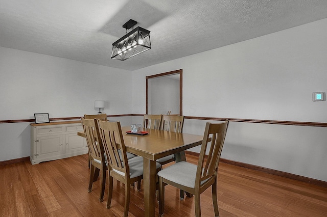 dining space with a chandelier, a textured ceiling, and light hardwood / wood-style floors