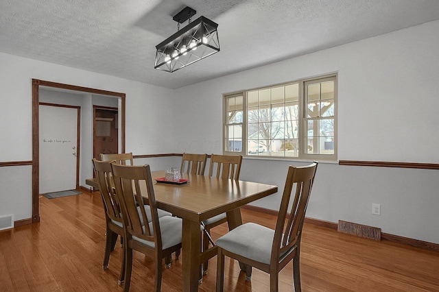 dining space featuring hardwood / wood-style flooring, a chandelier, and a textured ceiling