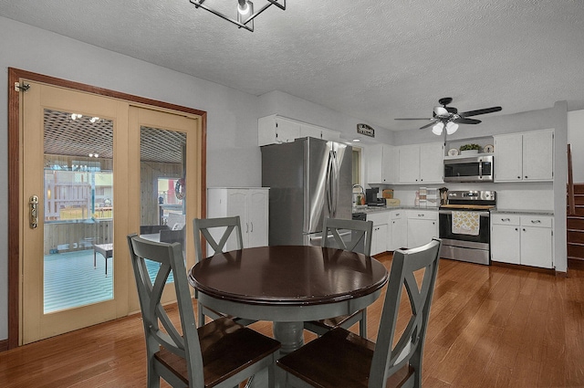 dining space featuring dark wood-type flooring, ceiling fan, and a textured ceiling