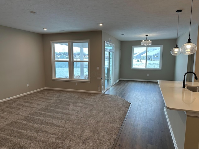 unfurnished living room with a textured ceiling, sink, plenty of natural light, and a notable chandelier