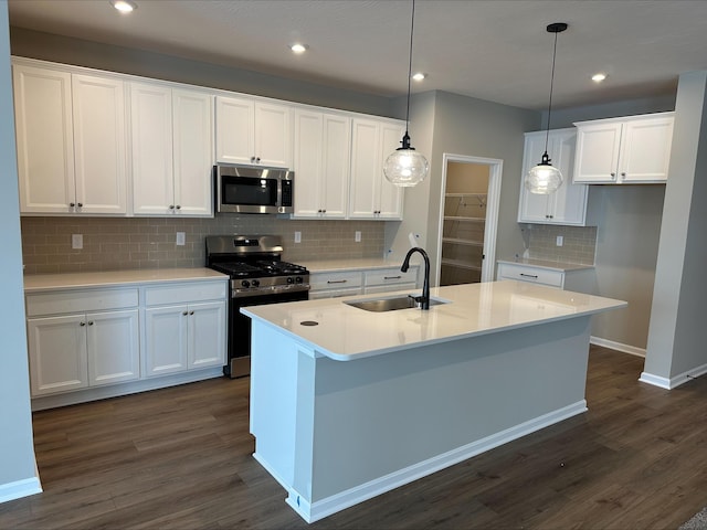 kitchen with appliances with stainless steel finishes, white cabinetry, a kitchen island with sink, and sink