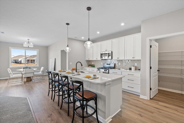 kitchen with stainless steel appliances, a sink, light countertops, backsplash, and a kitchen bar