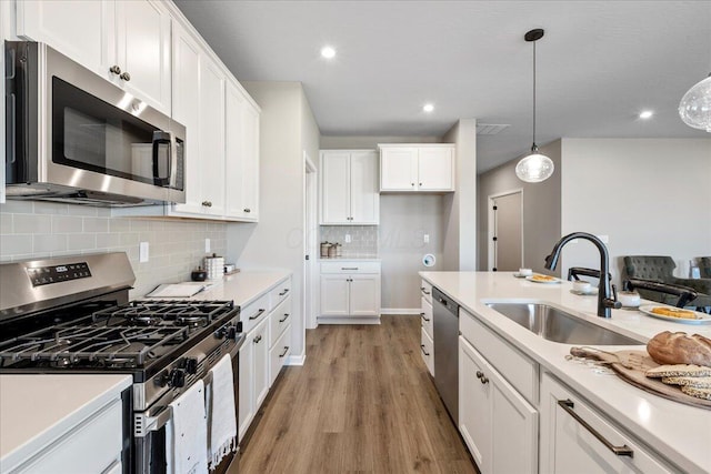 kitchen with stainless steel appliances, a sink, white cabinetry, and light wood-style floors