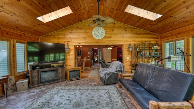 living room with a skylight, ceiling fan, and wood walls