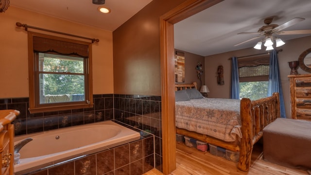 bathroom featuring hardwood / wood-style floors, a relaxing tiled tub, and a wealth of natural light