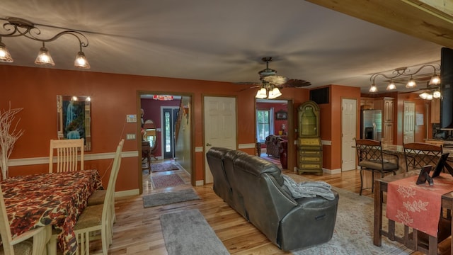 living room featuring beamed ceiling, ceiling fan, and light wood-type flooring