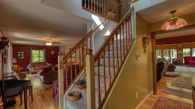 stairs with ceiling fan and hardwood / wood-style flooring