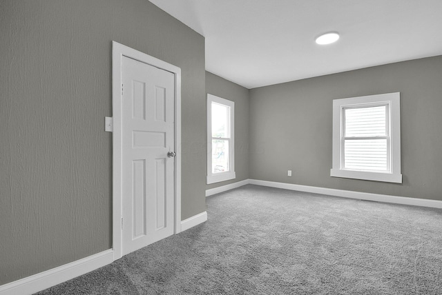 carpeted spare room featuring baseboards