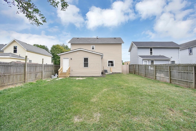 rear view of house featuring a lawn, a fenced backyard, and entry steps