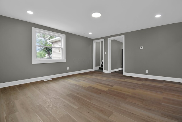 empty room with stairway, recessed lighting, wood finished floors, and baseboards