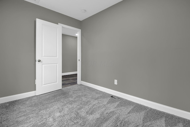 carpeted empty room featuring baseboards