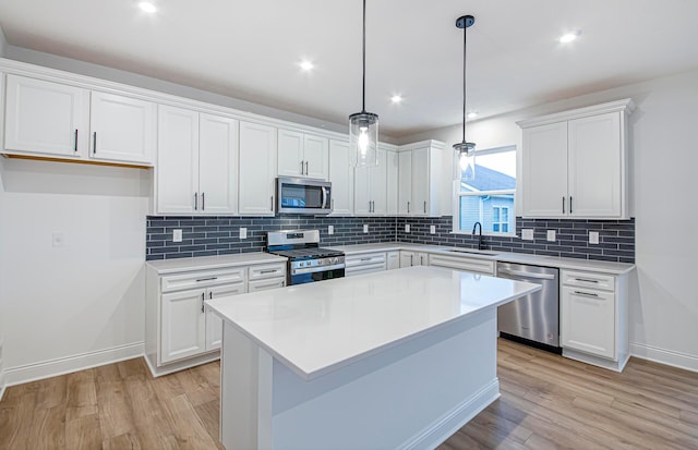 kitchen featuring hanging light fixtures, white cabinets, stainless steel appliances, and light hardwood / wood-style floors