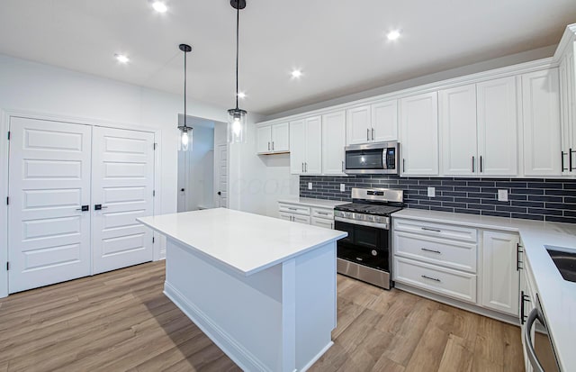 kitchen with white cabinets, light hardwood / wood-style floors, and appliances with stainless steel finishes