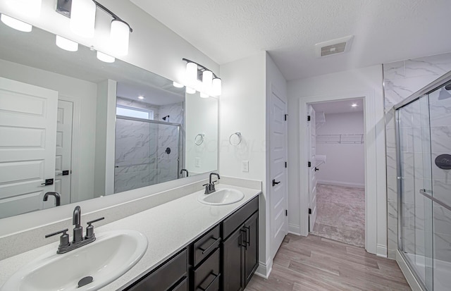 bathroom with hardwood / wood-style floors, vanity, walk in shower, and a textured ceiling